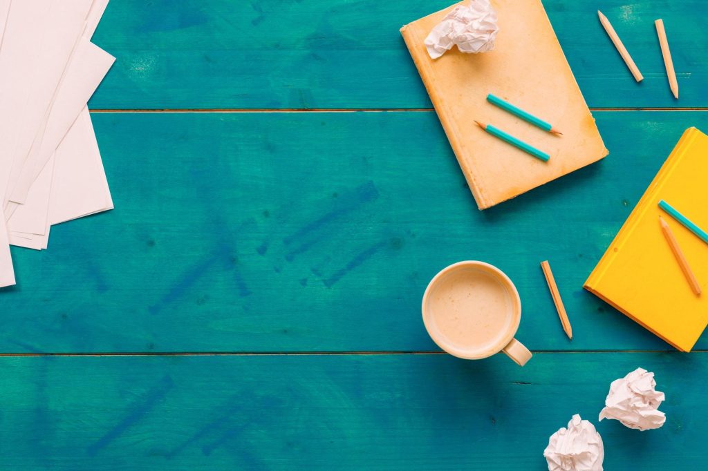 Writer's block concept, top view of books, crumpled paper and coffee cup on author's desk